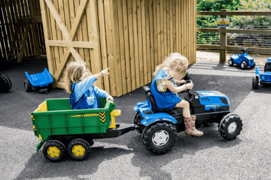 two young girls on pedal tractors